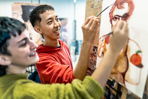 jóvenes estudiantes pintan sobre lienzo durante la lección en la facultad de artes de la universidad - concepto de aprendizaje y educación - art university studio domestic room fotografías e imágenes de stock