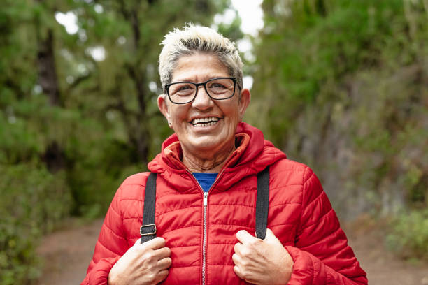 feliz mujer mayor que tiene durante el día de actividades de trekking en el bosque - concepto de gente de aventura y viaje - footpath hiking walking exercising fotografías e imágenes de stock