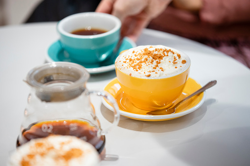 A close-up shot of three cups of coffee on a table in a coffee shop.