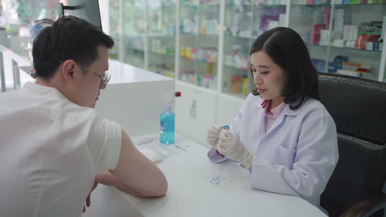Confident Asian woman pharmacist prepares to give Malaria, Tetanus, Typhoid, Hepatitis vaccine young to man.