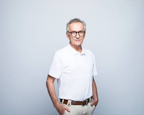 Portrait handsome smiling 50 years old mature man with stylish gray hair wearing red hipster glasses looking at camera isolated on blue background. Vision concept