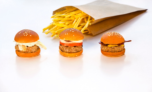 Delicious mini burgers with frenc fries on white background