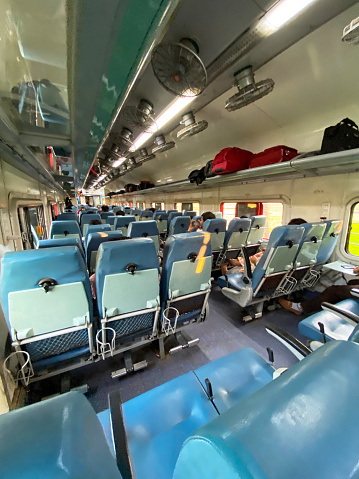 Stock photo showing the interior view of an Indian railway carriage with overhead electric fans and open baggage compartment.