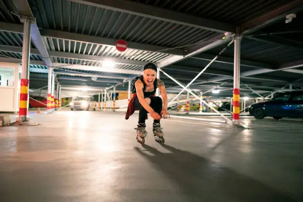 Young, enthusiastic, Caucasian woman having fun while roller-skating in a parking lot of a public garage.