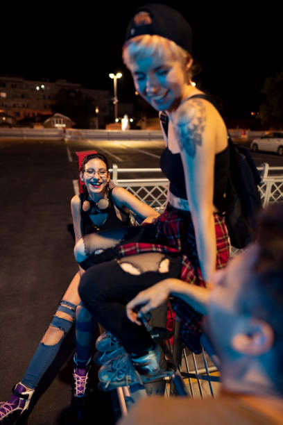 istock Smiling women on roller skates sitting with their friend 1387080521