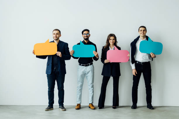 Beautiful young people are holding speech bubbles, looking at camera and smiling, on white background