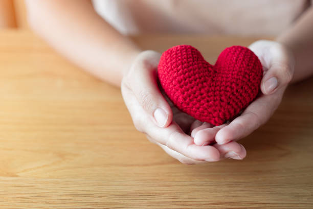 istock Adult hands holding a yarn red heart 1387083356