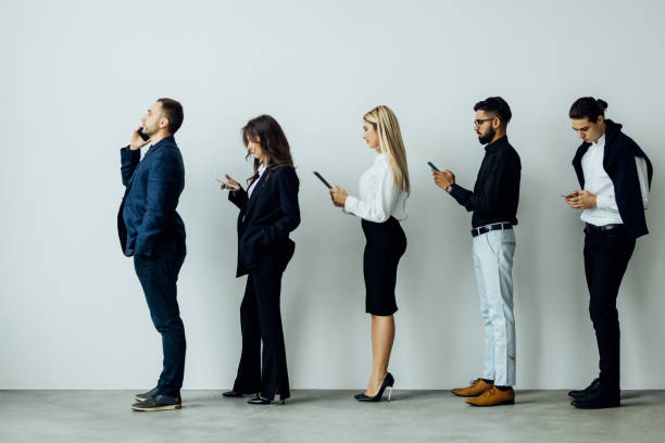 istock Businessmen on a line using their cellphones in queue 1387083362