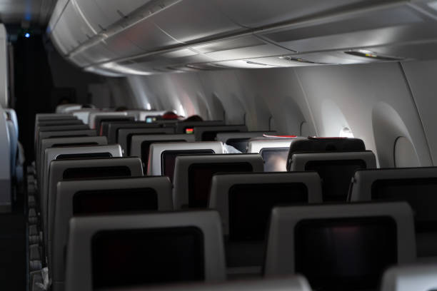 istock Airplane interior with rows of three seats by window 1387084015
