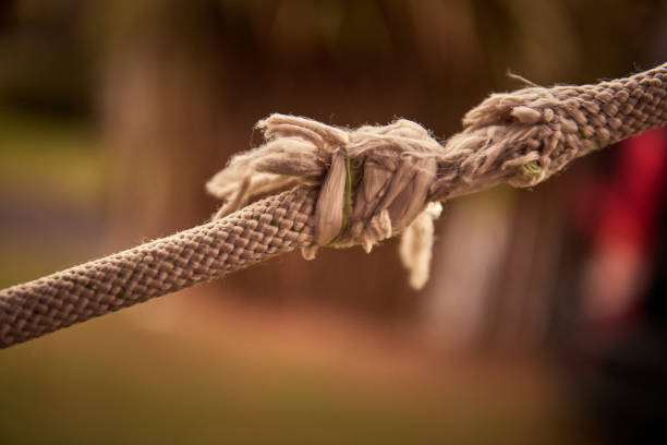 primer plano de una cuerda cortada y deshilachada a punto de romperse con el fondo borroso y el espacio de copia. horizontal. concepto de problema, estrés, divorcio. - rope frayed emotional stress breaking fotografías e imágenes de stock