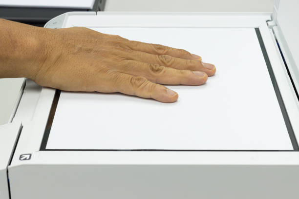 istock Hand holding a paper, inserting a scanner concept scanner for office automation 1387085695