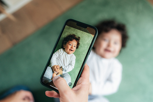 Mother taking photos of her baby using smartphone at home.