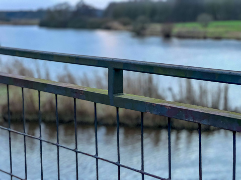 A bridge railing with a beautiful river in the background.