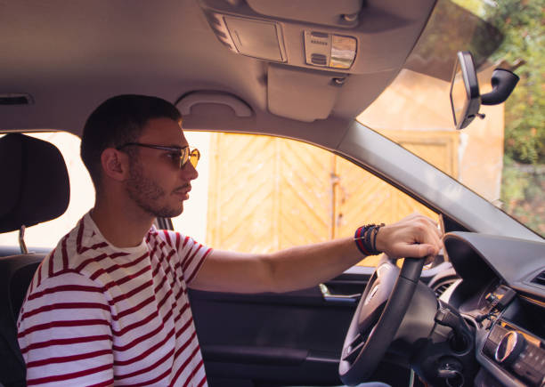 jovem bonito estacionando o carro - car driving men reversing - fotografias e filmes do acervo