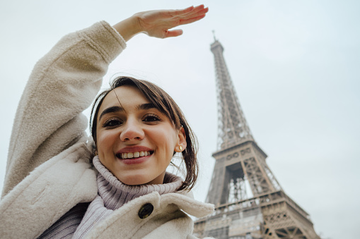 Self-portrait photo of a young woman in front of The Eiffel Tower in Paris, France.