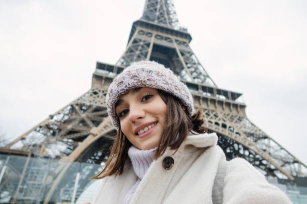 Self-portrait photo of a young woman in front of The Eiffel Tower in Paris, France.