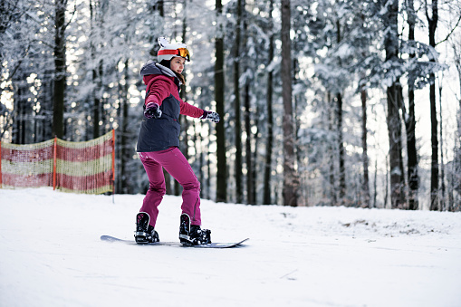 Teenage girl enjoying snowboarding on a winter day.\nCanon R5