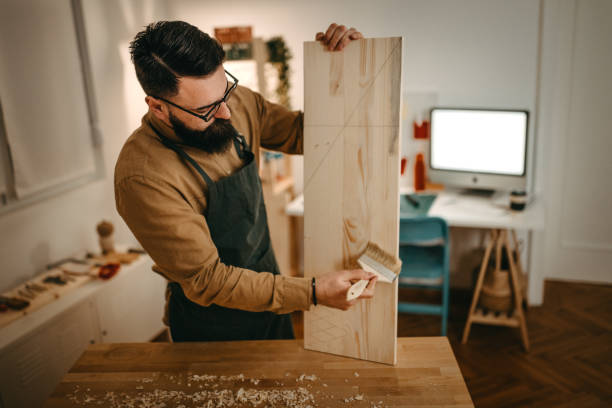 Male artist cleaning dust from wood on workbench in studio stock photo