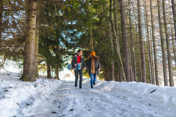 istock Beautiful young heterosexual couple running through a snowy forest while holding hands 1387096423