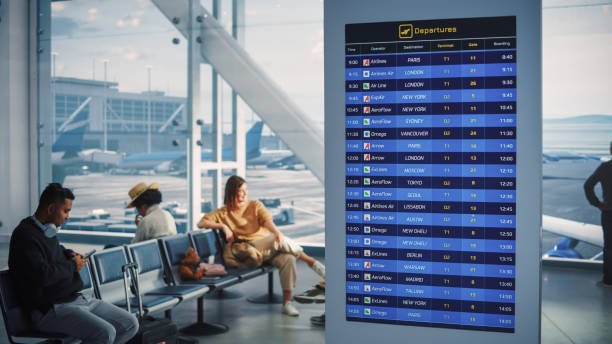 Airport Terminal: Arrival, Departure Information Display Showing all the Useful Flight Data For Travelers. Backgrond: Diverse Crowd of People Wait for their Flights in Boarding Lounge of Airline Hub terminal del aeropuerto: llegada, pantalla de información de salida que muestra todos los datos de vuelo útiles para los viajeros. backgrond: diversa multitud de personas esperan sus vuelos en la sala de embarque del centro de operaciones de airline hub