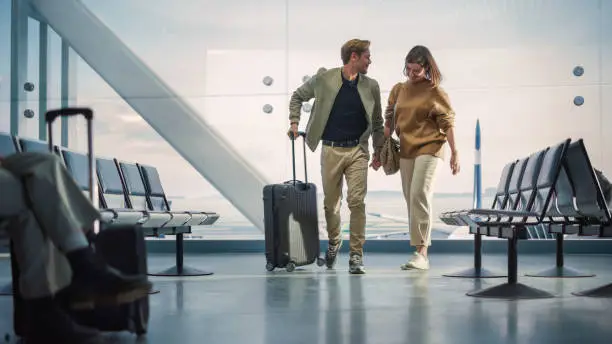 Photo of Airport Terminal Family Reunion: Beauitful Couple Meets at the Boarding Lounge. Smiling Girlfiend Meets the Love of Her Life after Long Parting and Hugs and Dances with Her Handsome Partner