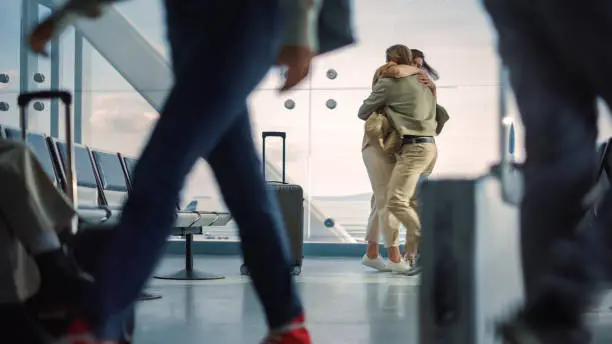Airport Terminal Family Reunion: Beauitful Couple Meets at the Boarding Lounge. Smiling Girlfiend Meets the Love of Her Life after Long Parting and Hugs and Dances with Her Handsome Partner