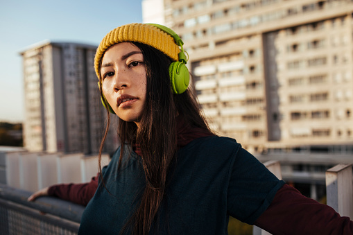 Young modern woman posing on rooftop and listening favorite song