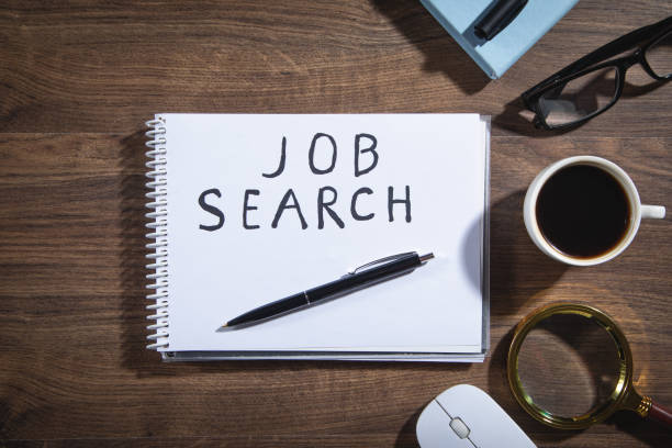 istock Job Search text on notepad with a magnifying glass, pen and other objects. 1387105306
