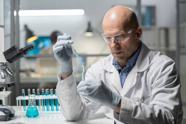 istock Mature experienced scientist in protective workwear mixing chemical substances 1387108181