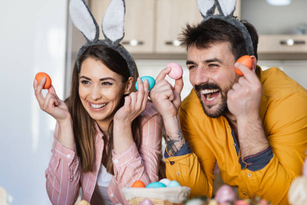 istock Young attractive couple holding colorful Easter eggs in their hands 1387108432