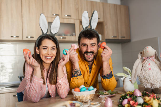 istock Attractive young couple wearing bunny ears holding up colorful Easter eggs 1387109599