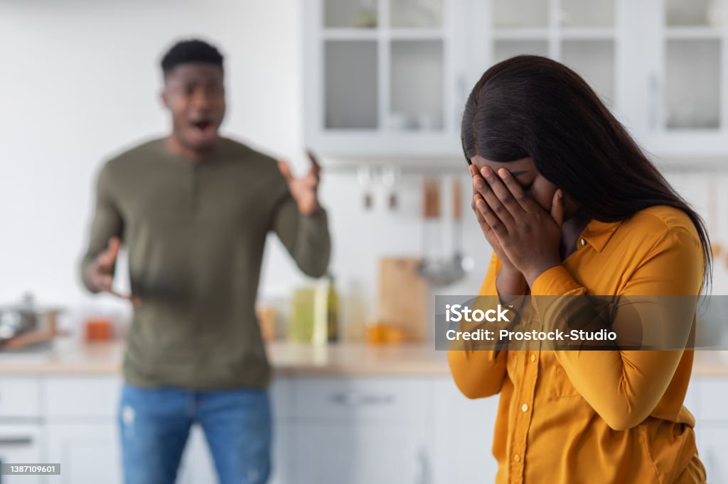 Psychological Violence. Black Young Woman Covering Face While Boyfriend Shouting At Her Psychological Violence. Black Young Woman Covering Face While Boyfriend Shouting At Her, African American Couple Arguing In Kitchen Interior, Suffering Marriage Crisis, Selective Focus On Female Couple - Relationship Stock Photo
