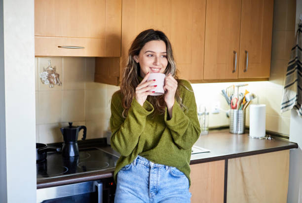 istock Beautiful woman drinking coffee in kitchen at home 1387109733