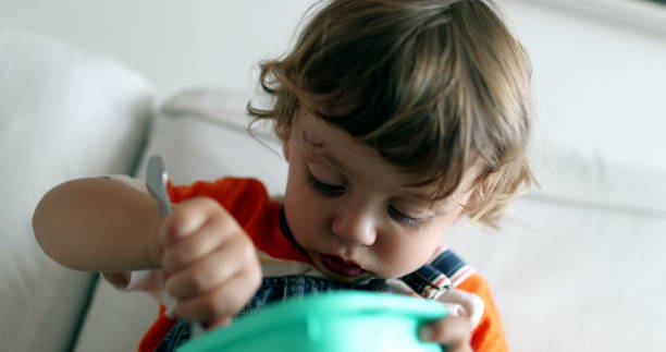 istock Adorable toddler boy eating healthy fruit snack with fork 1387110695