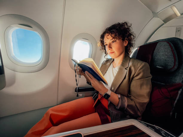 eine schöne geschäftsfrau, die ihre notizen liest, während sie mit dem flugzeug reist - commercial airplane airplane business travel flying stock-fotos und bilder