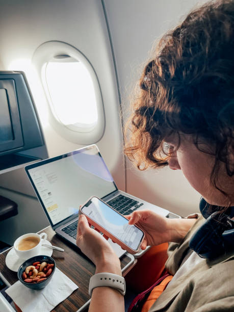 istock An Anonymous Female Working On Her Mobile Phone And Computer While Flying In An Airplane. 1387110861