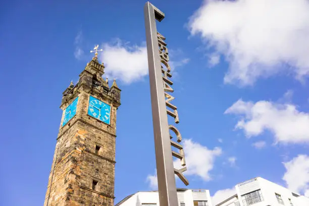 A sign for Merchant City in front of the historic Tollbooth Steeple.