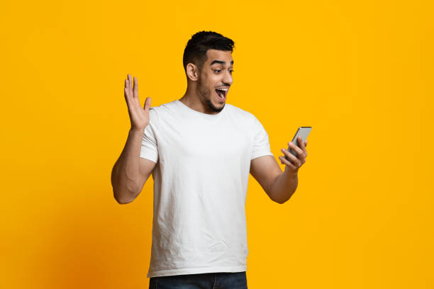 istock Emotional arabic guy gambling online on yellow background 1387112085