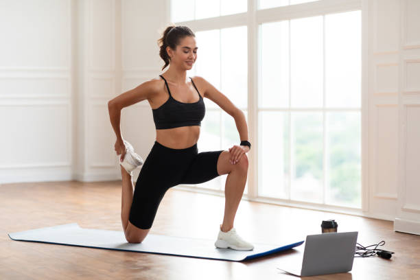 istock Cheerful woman stretching leg muscles using pc 1387112125