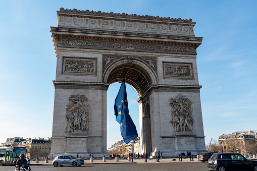Paris, France - March 10 2022: European Union flag flying in the wind under the Arc de Triomphe in March 2022 for a special EU summit on Ukrainian crisis