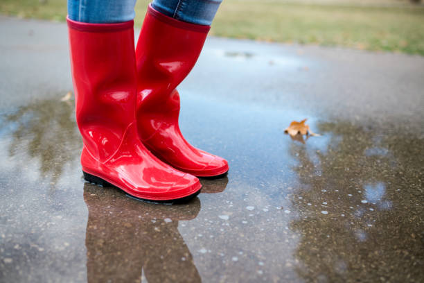 Rubber boots are jumping into a big puddle with splash.