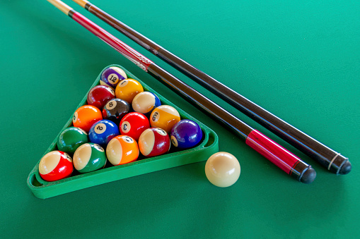 Billiard balls and cue sticks on green broadcloth.