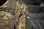 Ukrainian flag on a military uniform, war. Soldier Armed Forces of Ukraine. Territorial defense