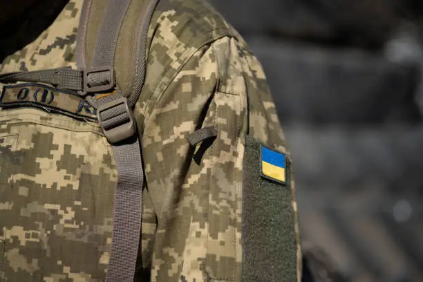 Photo of Ukrainian flag on a military uniform, war. Soldier Armed Forces of Ukraine. Territorial defense