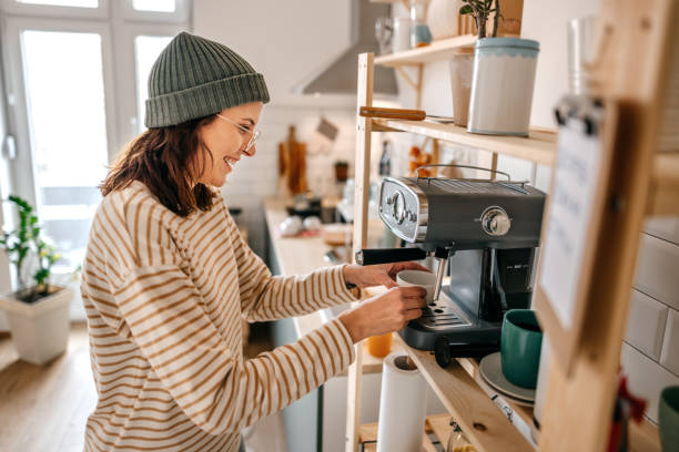 istock Woman preparing coffee through machine in kitchen 1387120601