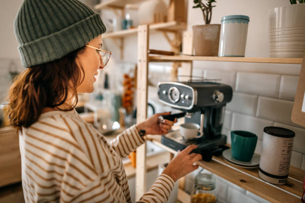 istock Woman preparing coffee through machine in kitchen 1387120636