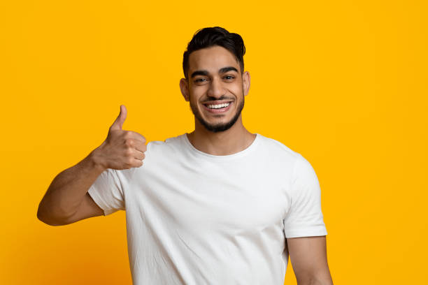 istock Handsome young middle eastern guy showing thumb up on yellow 1387120649