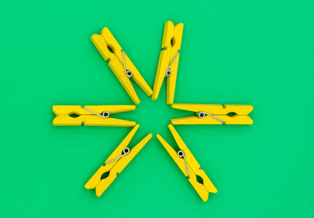 Yellow colorful wooden clothespins on a green background