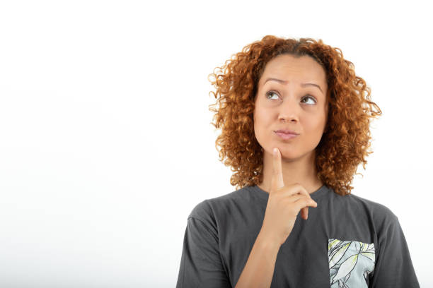 istock Woman with thoughtful expression looking up with hand on chin 1387123830