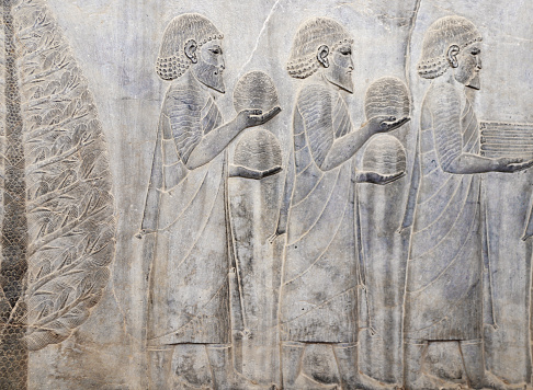 Ancient wall with bas-relief with assyrian foreign ambassadors with gifts and donations, Persepolis, Iran. UNESCO world heritage site